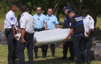 File photo shows French gendarmes and police who carry a large piece of plane debris which was found on the beach in Saint-Andre, on the French Indian Ocean island of La Reunion